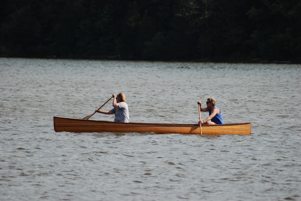 man and woman riding on brown boat on lake during daytime