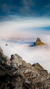 person in black jacket and blue denim jeans standing on rock formation during daytime