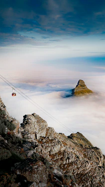 person in black jacket and blue denim jeans standing on rock formation during daytime