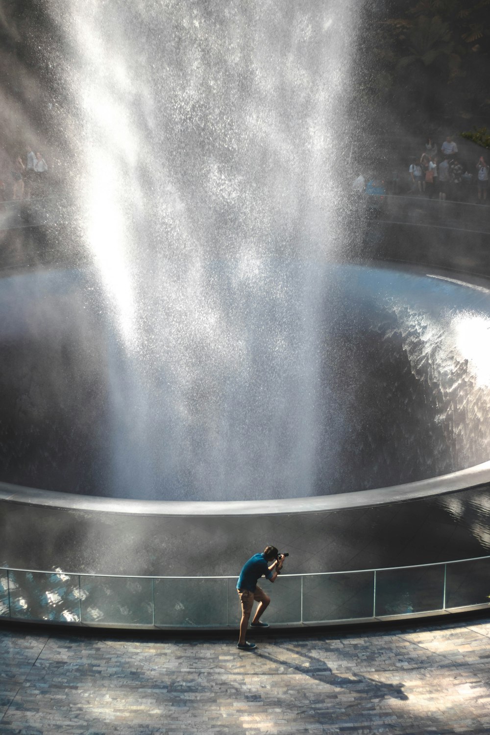 boy in blue t-shirt and black shorts standing on water fountain during daytime