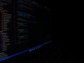 A close-up of a cybersecurity expert analyzing code on a computer screen in a dimly lit environment.