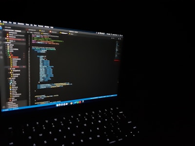 A sleek laptop displaying code on a dark background.