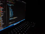 A sleek, minimalist icon representing coding with glowing lines on a dark blurred background.