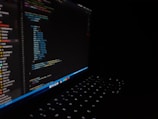 Hands typing code on a laptop with AI graphics.