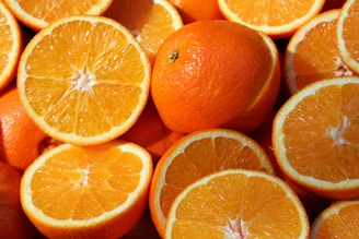 A close-up view of several whole and halved oranges with vibrant orange peel and juicy segments, showcasing freshness and nutrition.