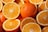A close-up view of several whole and halved oranges with vibrant orange peel and juicy segments, showcasing freshness and nutrition.