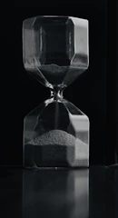 An artistic hourglass casting long shadows on a textured surface.