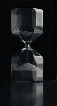 An artistic hourglass casting long shadows on a textured surface.