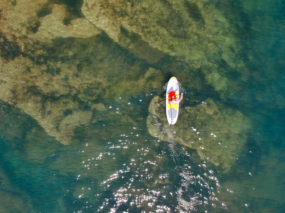 Person, die tagsüber weißes und rotes Kajak auf dem Wasser fährt