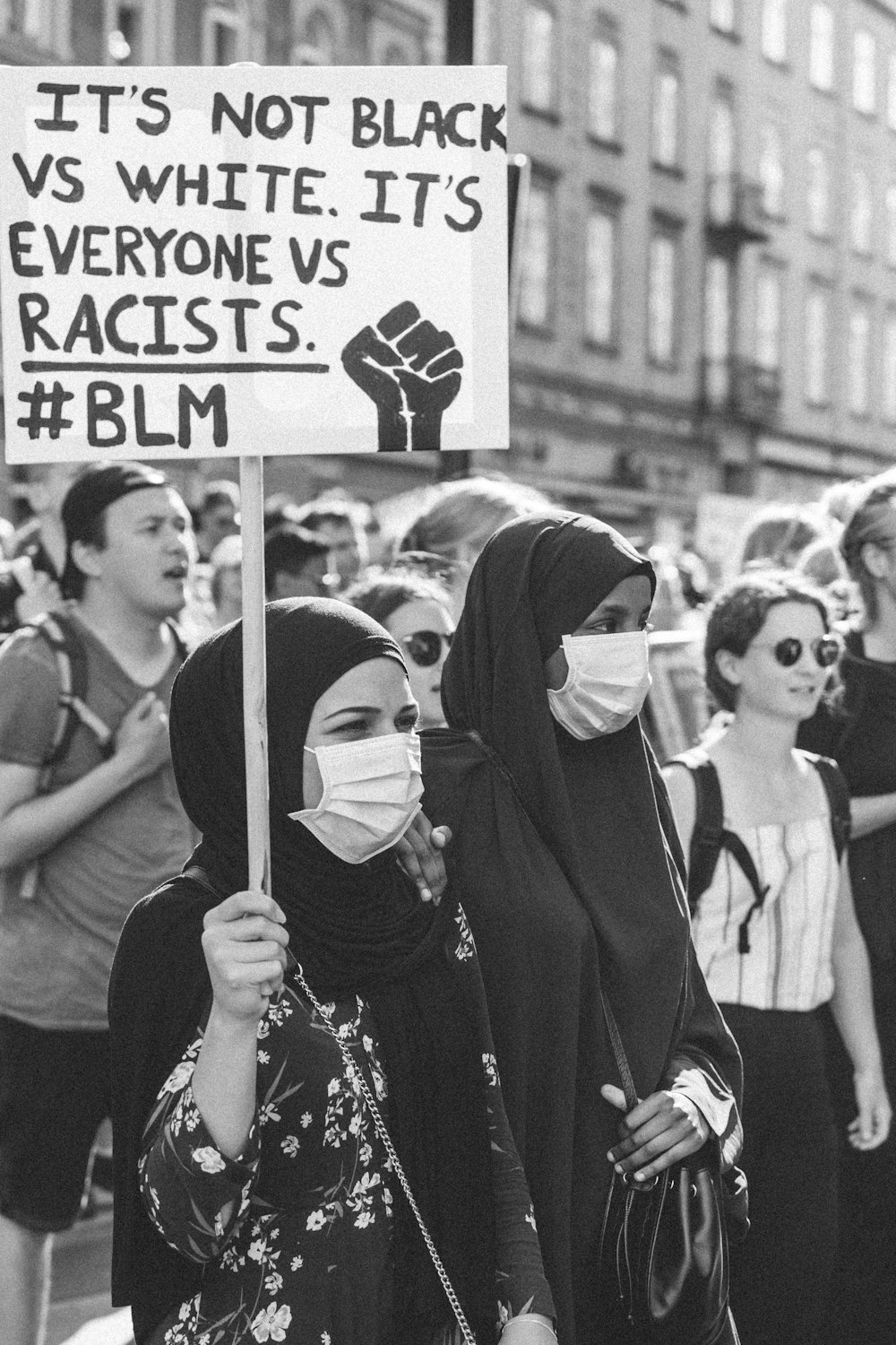 woman in black hijab holding white and black banner