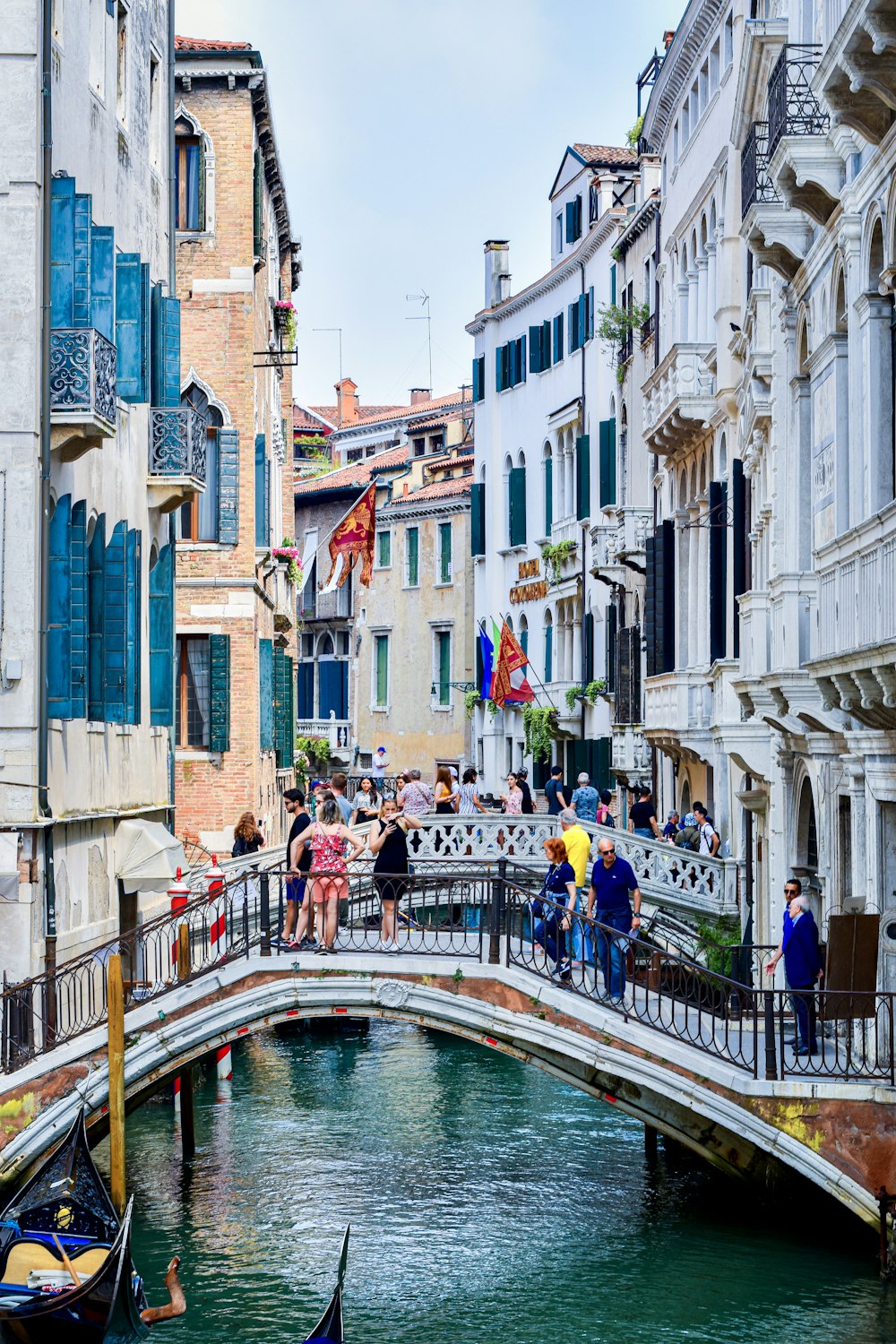 people in boat on river between buildings during daytime