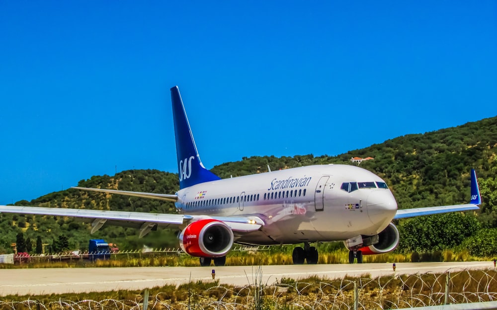 white and blue passenger plane on brown field under blue sky during daytime