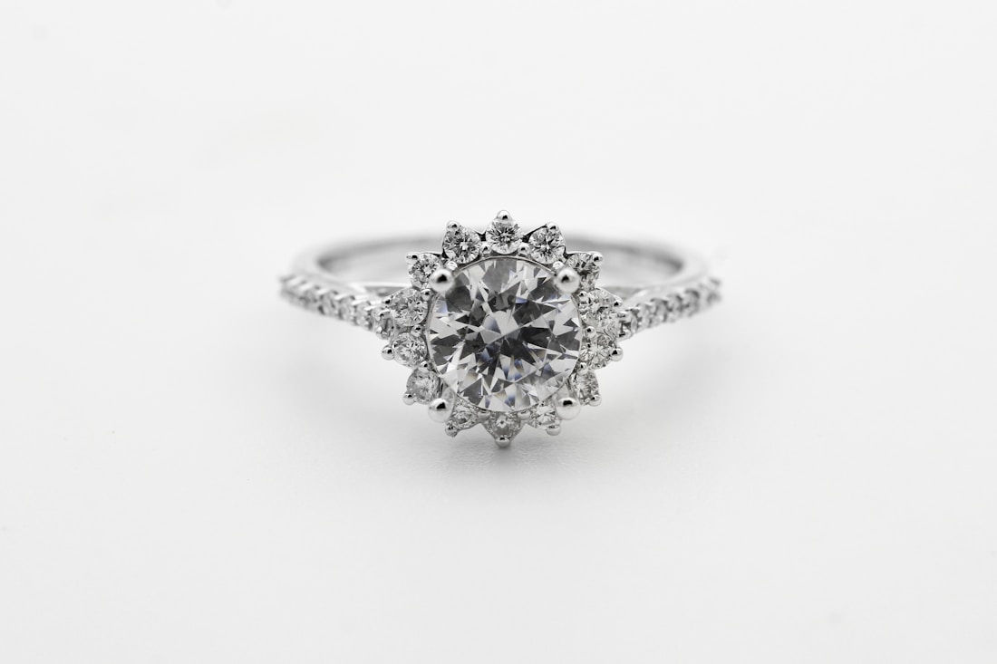 Round-brilliant diamond with hand-set sunburst halo on a white gold band