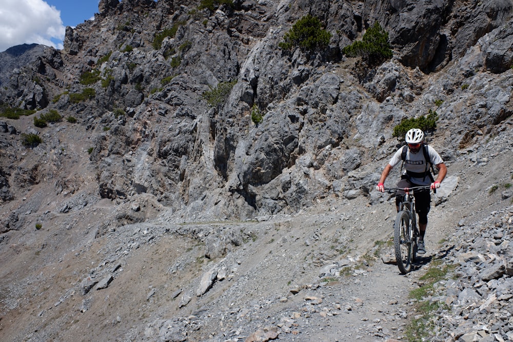 man in black and white shirt riding mountain bike on rocky mountain during daytime