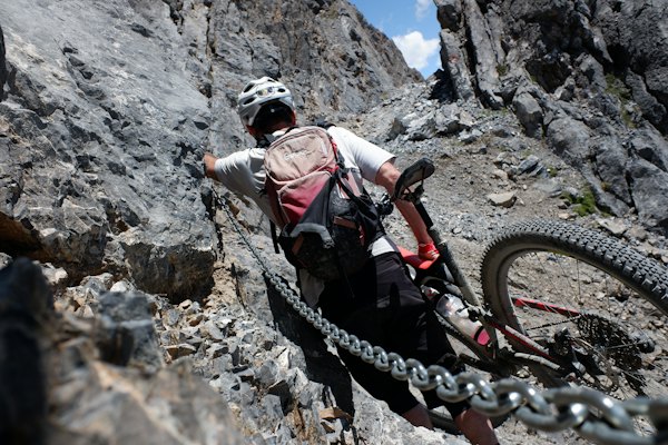 Man in white shirt and black pants with black helmet climbing mountain during daytime — Bormio, Italy