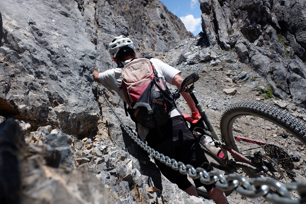 man in white shirt and black pants with black helmet climbing mountain during daytime