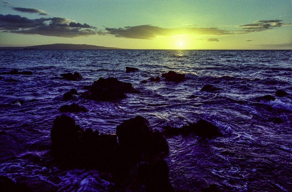 black rocks on sea under blue sky during daytime