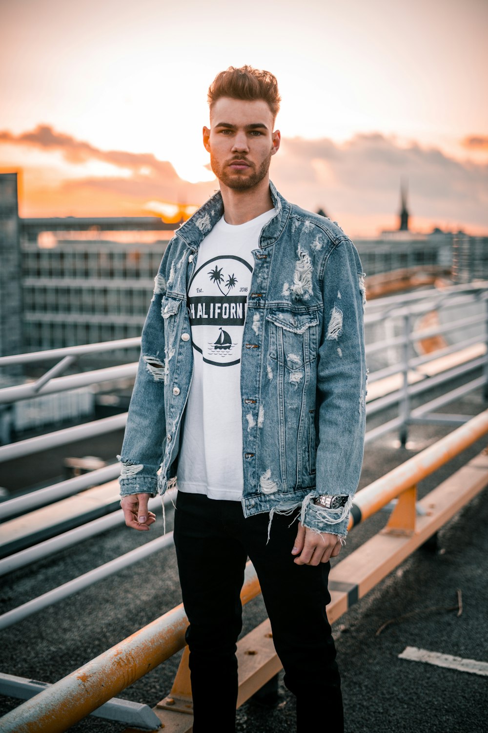 man in blue denim jacket standing on bridge during daytime