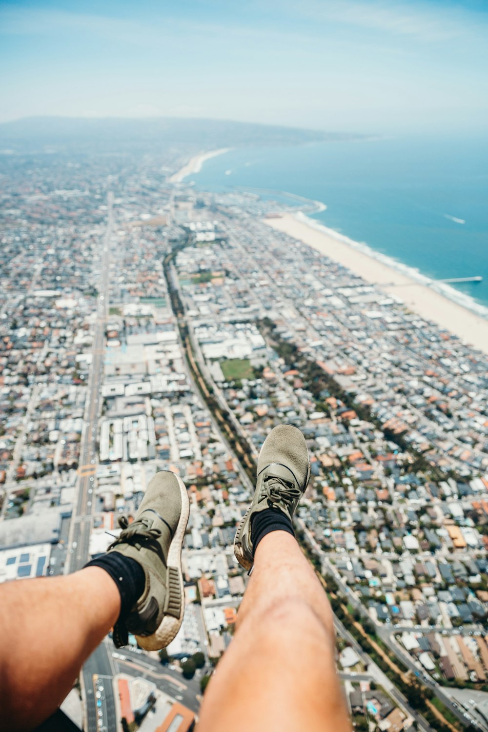 person in gray and white sneakers sitting on top of building during daytime