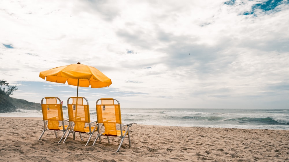 낮 동안 해변에서 노란색과 흰색 해변 의자