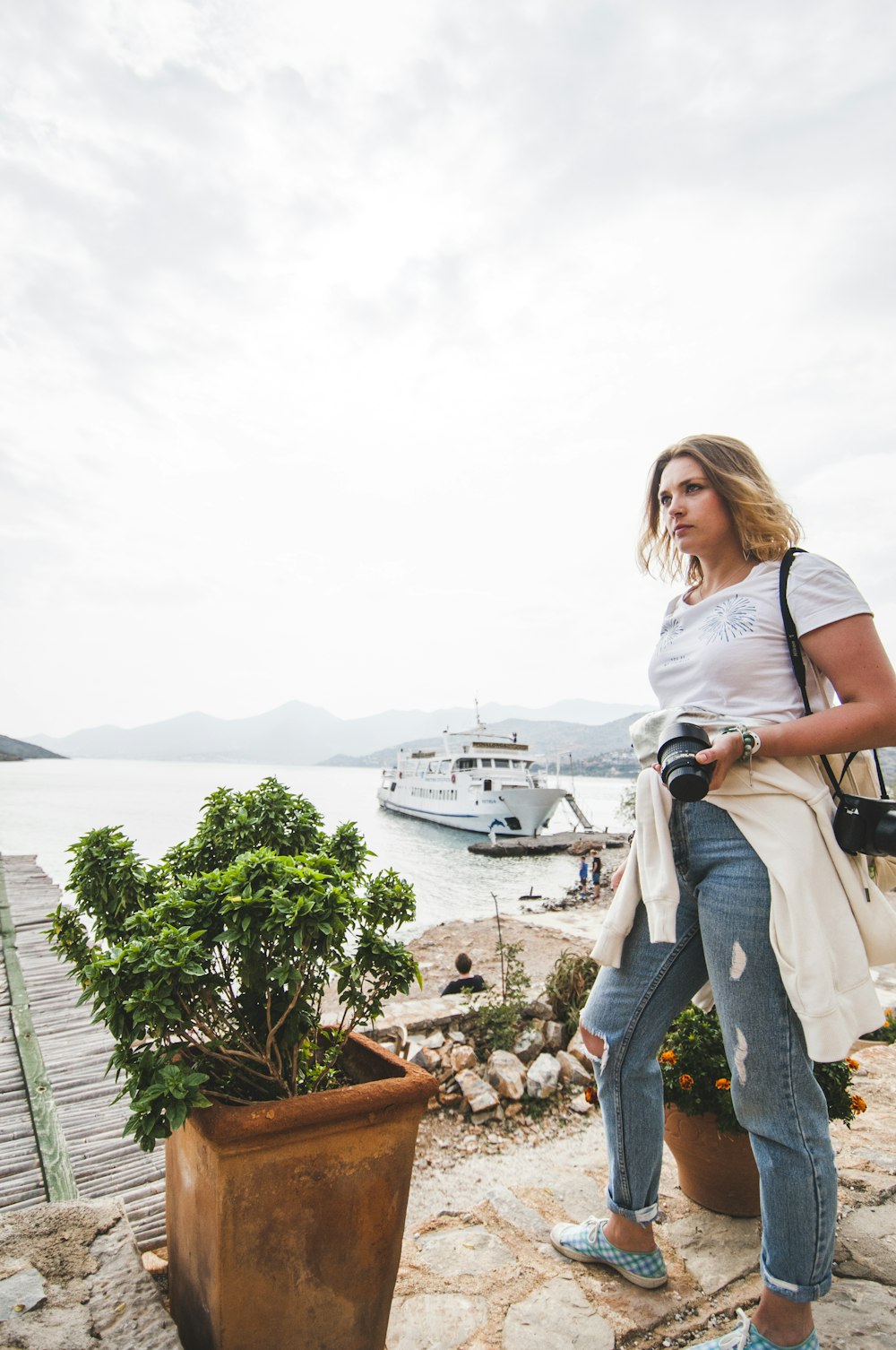 woman in blue denim jeans standing on brown wooden dock during daytime