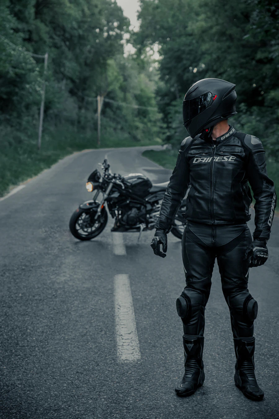 Man in a black leather jacket riding a motorcycle, embodying a rugged confident style
