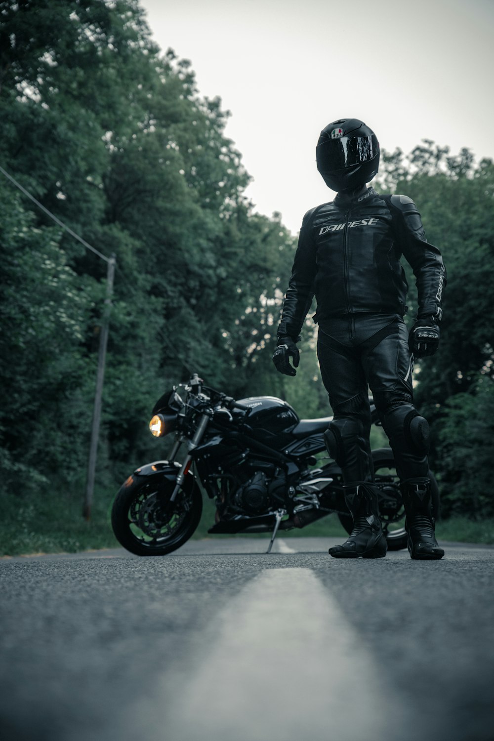 Mann in schwarzer Jacke und Helm fährt schwarzes Motorrad