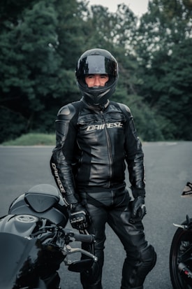man in black leather jacket and helmet riding motorcycle