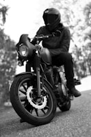 grayscale photo of man riding motorcycle