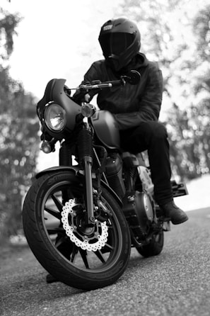 grayscale photo of man riding motorcycle