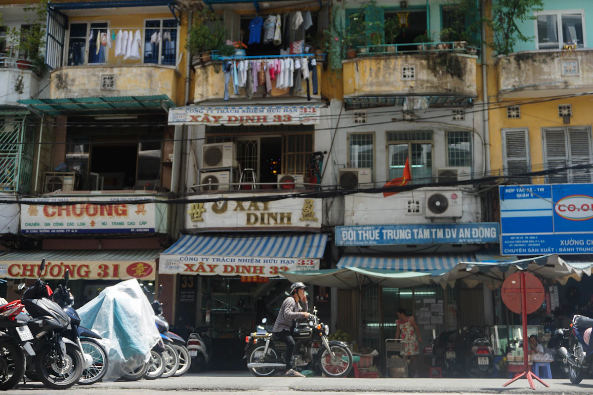 Motorcycles passing weathered shopfronts and apartment balconies in Ho Chi Minh City