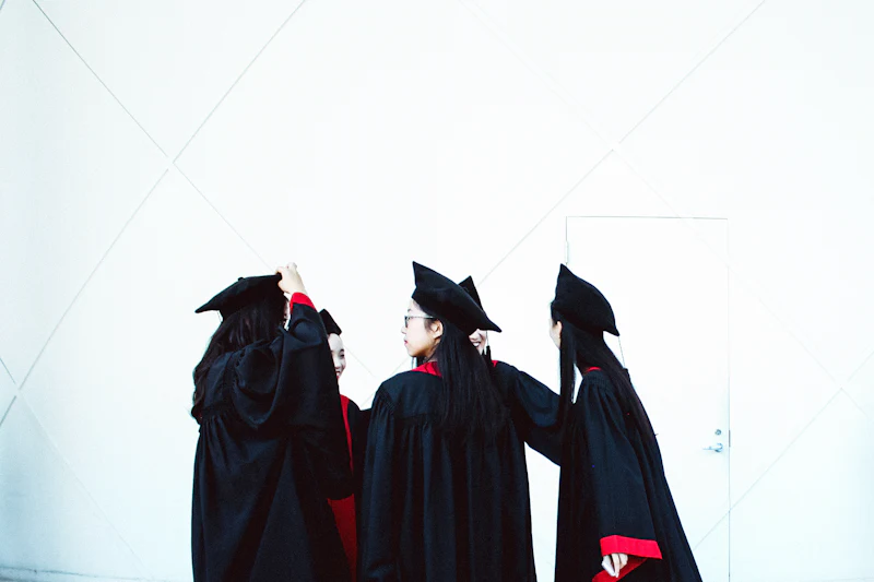 A law graduate in cap and gown holding a rolled diploma outside on convocation day