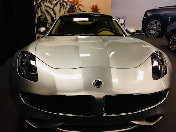Shiny, freshly polished sports car parked outside 800 paint and body shop with palm trees in background