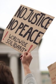 a person holding a sign that says no justice no peace
