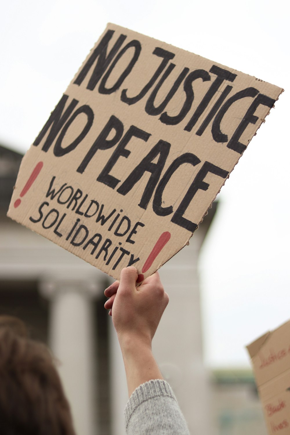 Una persona che regge un cartello che dice no justice no peace