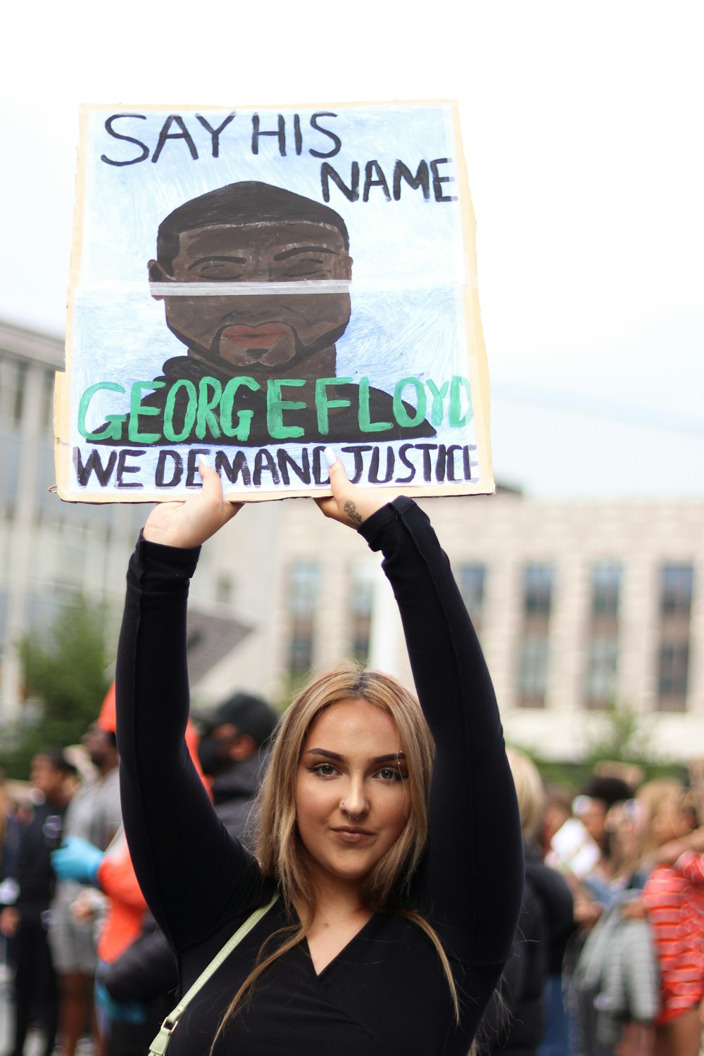 woman holding white and black welcome to the beach signage