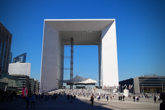 people walking on street near white concrete building during daytime in Grande Arche de la Defense France