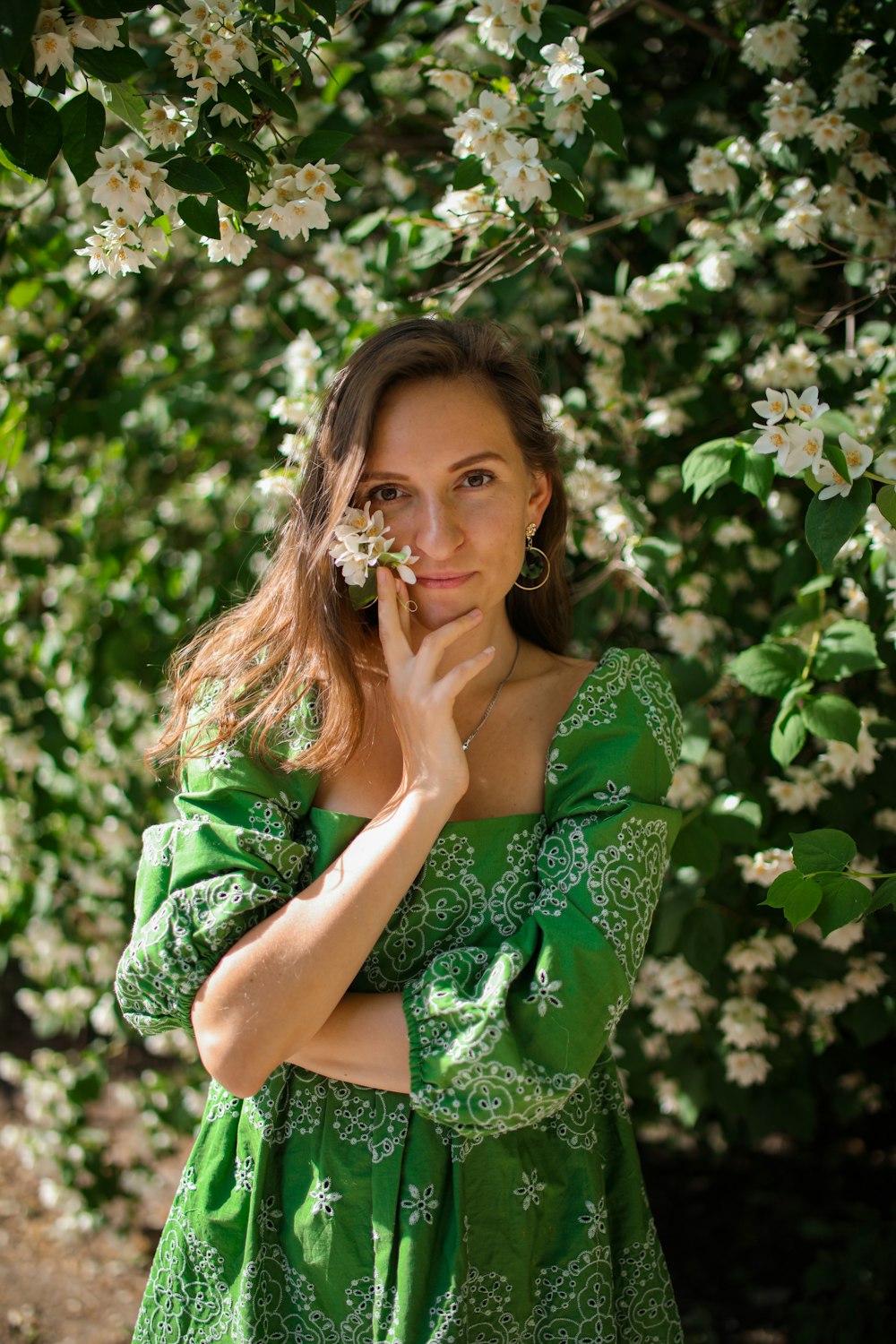 Frau in grün-weißem Blumenkleid, die tagsüber auf grünem Gras sitzt