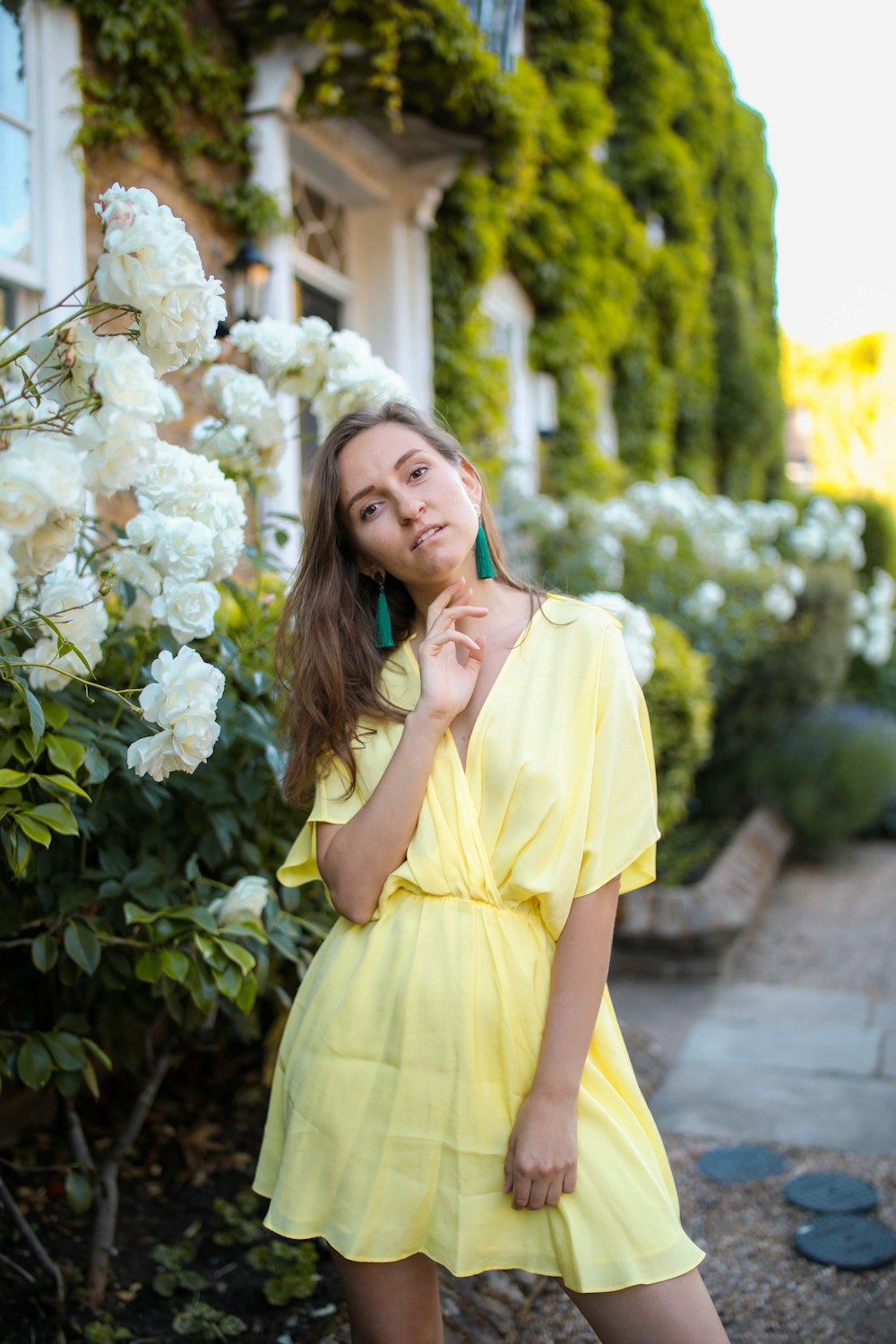 woman in yellow dress standing beside white flowers during daytime