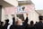 A group of people are participating in a protest, with one individual prominently holding a sign that reads 'The UK is not innocent' and lists several names. The setting appears to be an urban environment, with a focus on conveying a message of social justice.