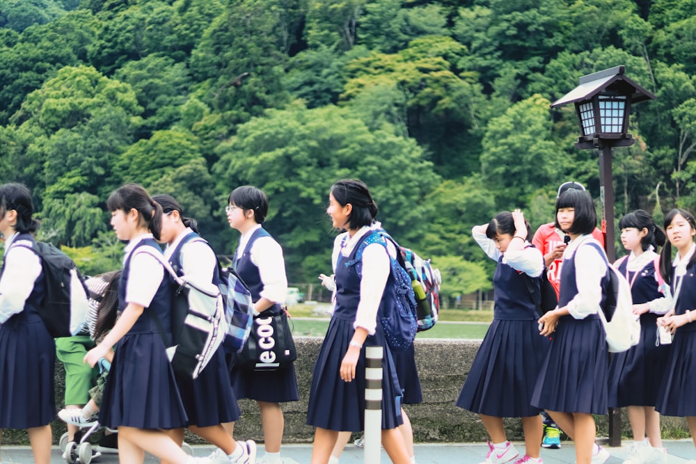 groupe de femmes en uniforme scolaire debout sur le champ d’herbe verte pendant la journée