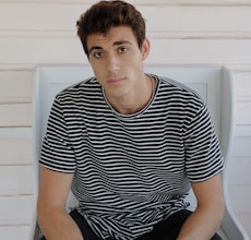 man in black and white striped crew neck t-shirt sitting on white plastic chair