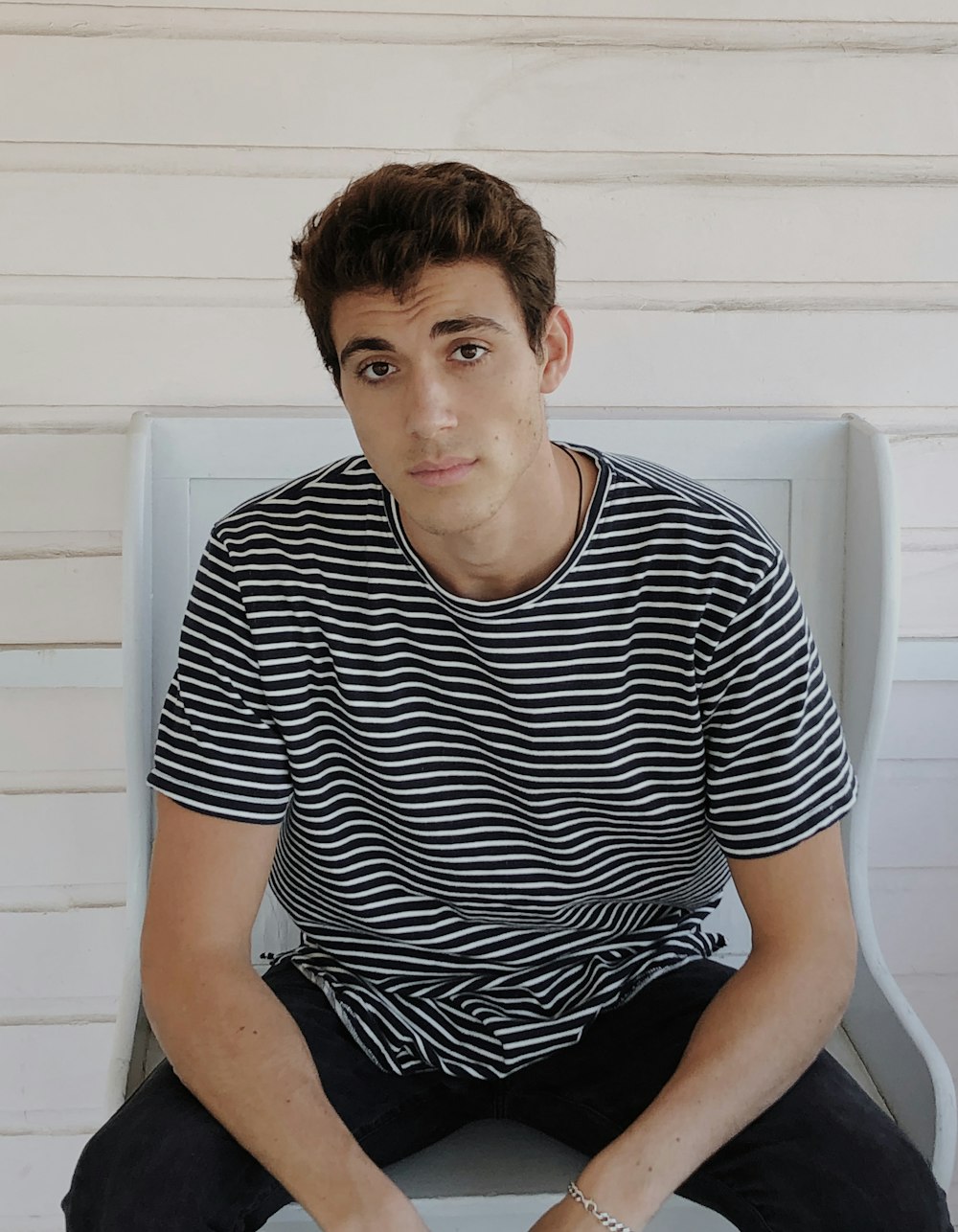 man in black and white striped crew neck t-shirt sitting on white plastic chair