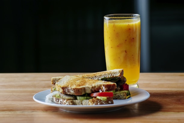 A close-up of a delicious sandwich and a fresh juice served on a wooden table.