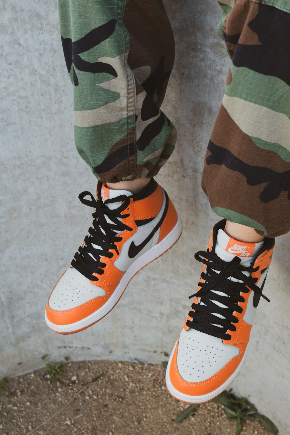 person in green black and brown camouflage pants wearing orange and white  nike sneakers photo – Free Clothing Image on Unsplash