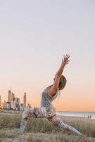 A woman practicing yoga on a beach at dawn.