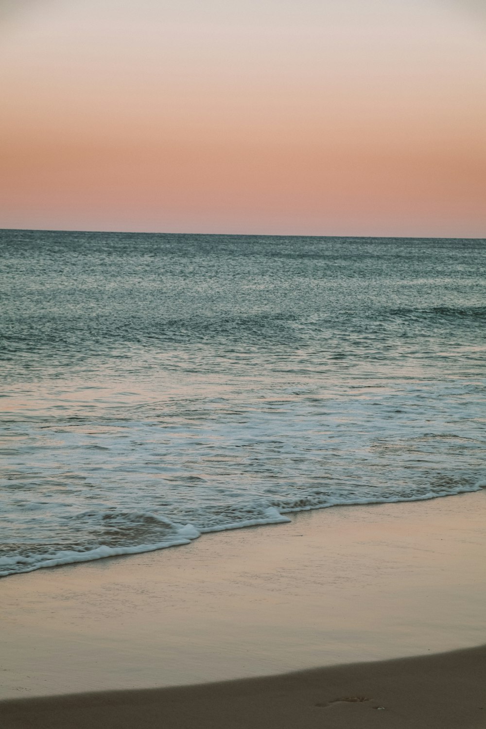 sea waves crashing on shore during sunset