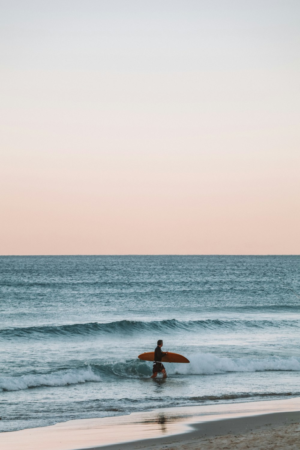 pessoa em shorts pretos surfando no mar durante o dia
