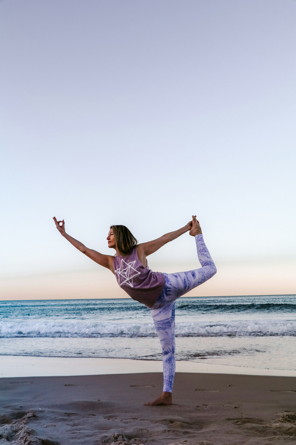 woman in purple long sleeve shirt and blue denim jeans jumping on beach during daytime