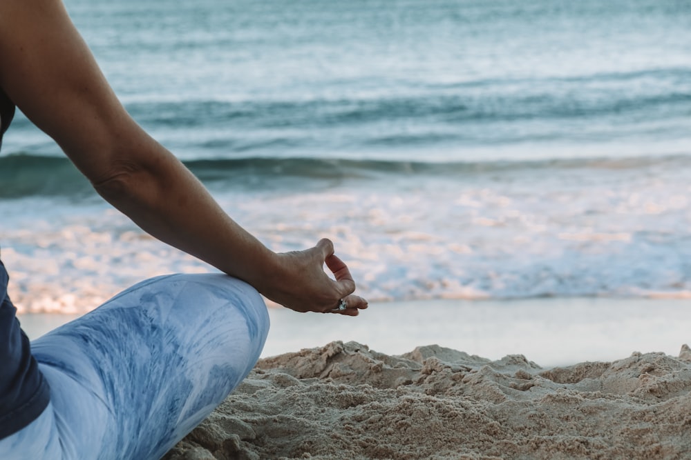 Persona in pantaloncini blu che si siede sulla spiaggia durante il giorno